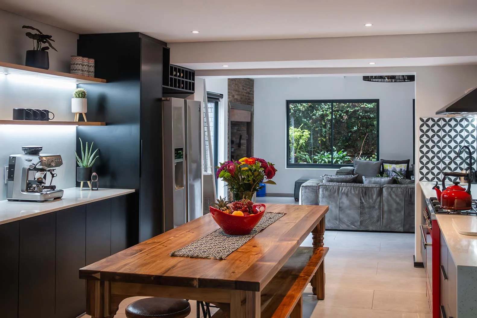 Completed kitchen with dark cabinetry, a timber dining table and an adjoining living space